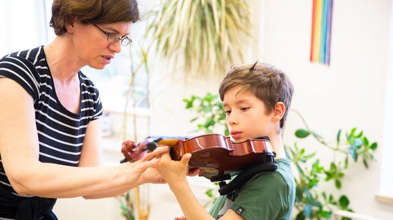 Maria Schalk, Lehrerin für Violine hilft einem Geigenkind bei der Instrumentenhaltung