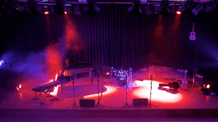 Bühne mit Flügel, Keyboard, Schlagzeug in rotem Scheinwerferlicht