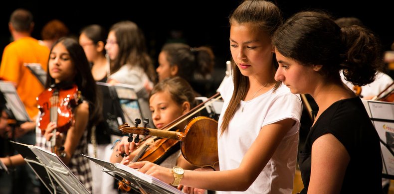zwei jugendliche Mädchen mit Geigen im Arm treffen letzte Absprachen vor dem Auftritt