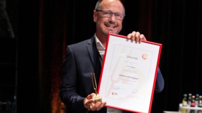 Robert Wagner mit der goldenen Stimmgabel des VdM und der dazugehörenden Urkunde