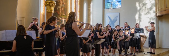 Schüler*innen mit Block- und Querflöten im Altarraum.