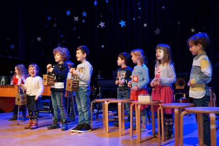 Singende Grundschulkinder mit verschiedenen Percussioninstrumenten in den Händen