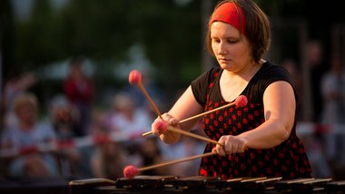 Frau spielt mit vier Schlägeln Marimbaphon