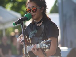 Junge Frau in rockiger Kleidung spielt E-Gitarre bei einem Open-Air-Konzert