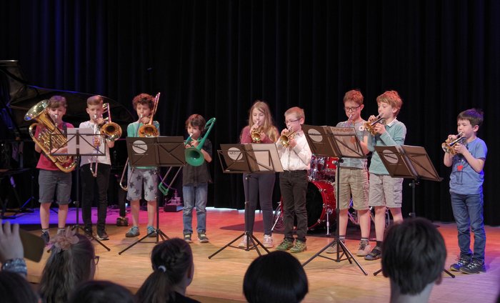 Kinder mit Blechblasinstrumenten stehen musizierend auf der Bühne