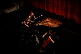 Blick von oben auf die Bühne. Es spielen ein Ensemble mit Querflöte, Cello und Klavier