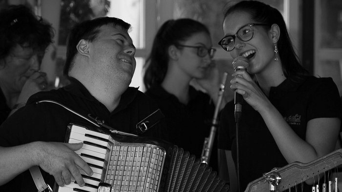 Eine Sängerin mit Mikro und ein Akkordeonist mit Down-Syndrom musizieren sich innig zugewandt