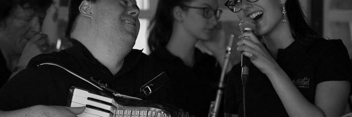 Eine Sängerin mit Mikro und ein Akkordeonist mit Down-Syndrom musizieren sich innig zugewandt