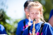 Maedchen spielt mit geschlossenen Augen Saxofon bei einem Auftritt im Freien