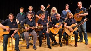 Ein Gruppenfoto des Ensembles Saitensprünge: Erwachsene und Senior:innen mit Gitarren