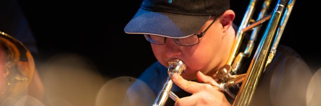 Junger Mann mit Käppi spielt Posaune