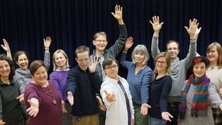 Gruppenbild Wellness-Chor: Erwachsene posieren mit ausgestreckten Armen