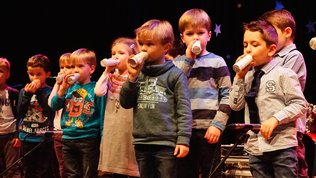 Kinder mit selbstgebasltelten Kazoos auf einer Bühne
