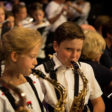 Junge spielt Saxofon und zwinkert in die Kamera