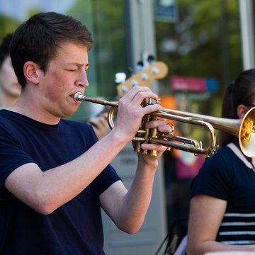 Junger Mann spielt mit geschlossenen Augen Trompete, im Hintergrund weitere Bandmitglider