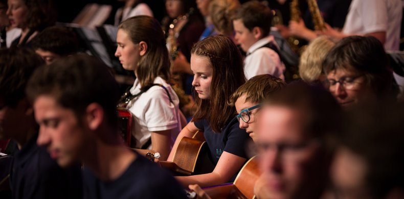 Kinder mit Gitarren im großen Orchester