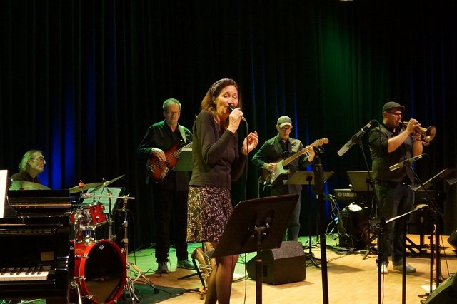 Gesangsdozentin Susanne Schönwiese, im Hintergrund die Band