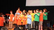 Kinderchor in bunten T-Shirts singt und gestikuliert