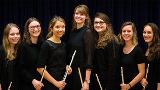 Ein Gruppenfoto des Ensembles Flöjtigen: jungen Frauen, schwarz gekleidet mit Querflöten in den Händen
