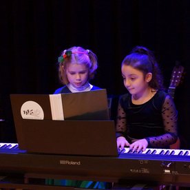 Zwei Mädchen spielen vierhändig an einem E-Piano