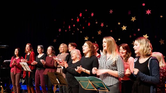 Der Gospelchor bei einem Auftritt, die  Mitglieder singen und klatschen