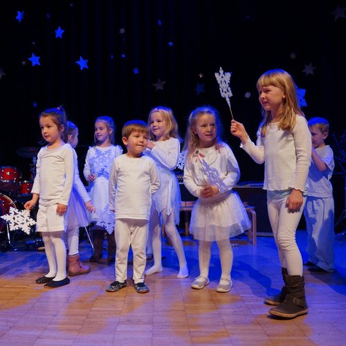 Kleinkinder mit weißen Klamotten und Papierschneeflocken in der Hand, Auftritt Weihnachtsfeier Musikschule
