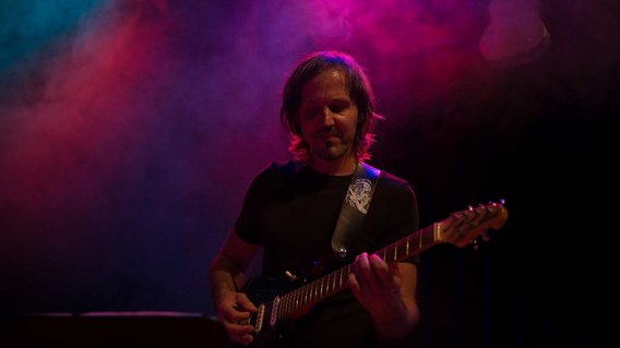 Gitarrenlehrer Marc Kassel steht mit E-Gitarre auf einer Bühne, gehüllt in Nebel 