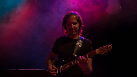 Gitarrenlehrer Marc Kassel steht mit E-Gitarre auf einer Bühne, gehüllt in Nebel