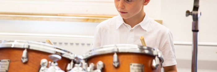 Junge im weißen Hemd am Schlagzeug