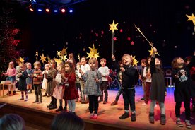 Viele Kinder auf der Bühne, sie halten gebastelte Sterne hoch