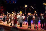 Viele Kinder auf der Bühne, sie halten gebastelte Sterne hoch