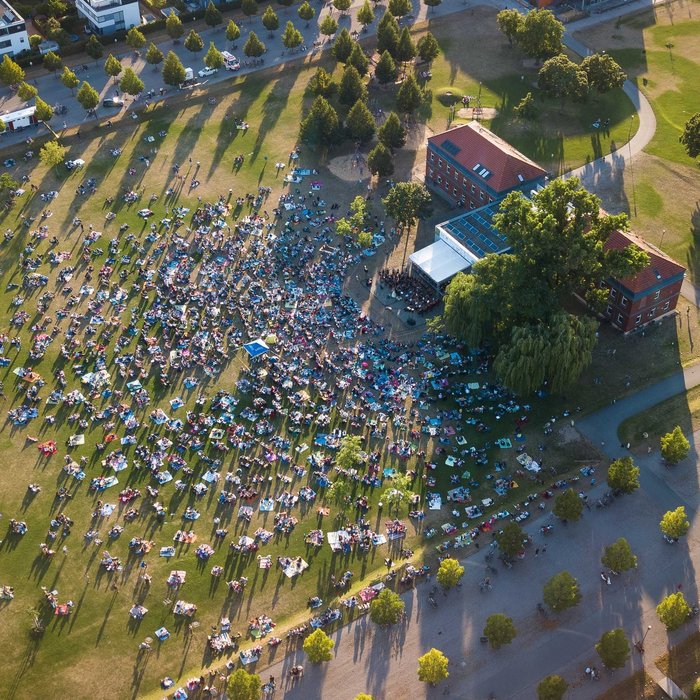 Südstadtpark mit Musikschulgebäude von oben, Menschen picknicken bei einem Open Air Konzert