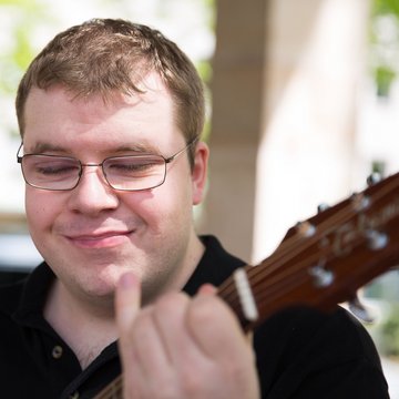 Junger mann mit Behinderung spielt Gitarre