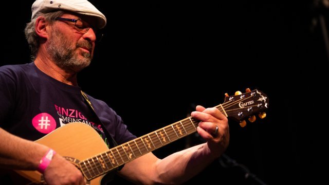 Mann mit grauem Bart spielt Gitarre