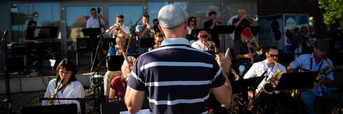 Big Band bei einem Open Air Konzert, im Zentrum der Dirigent von hinten 