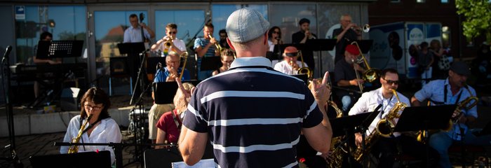 Big Band bei einem Open Air Konzert, im Zentrum der Dirigent von hinten 