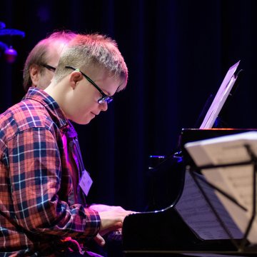 Junge mit Down-Syndrom spielt Klavier