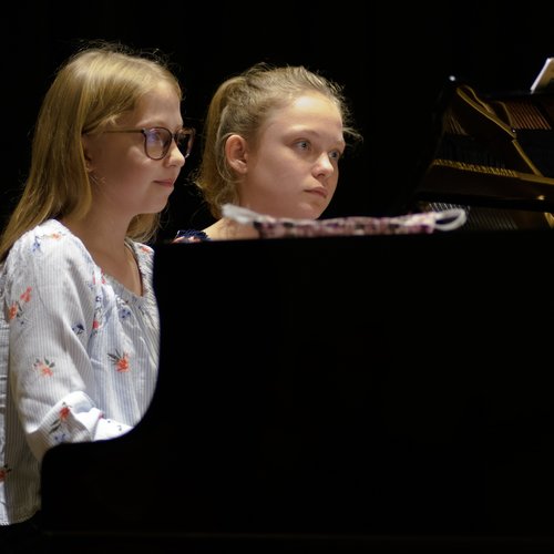 Zwei Mädchen spielenvierhändig am Klavier