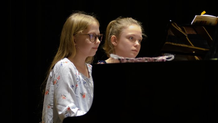 Zwei Mädchen spielen vierhändig Klavier