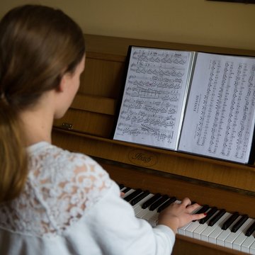 Rückenansicht von Mädchen das am Klavier sitzt