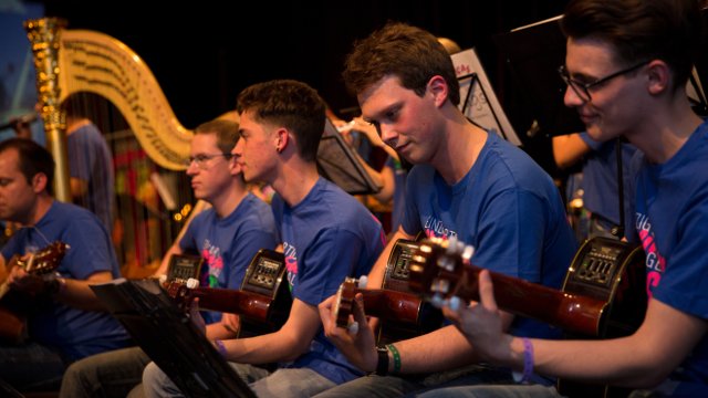 Junge Männer mit Gitarren, im Hintegrund die Harfe