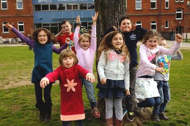 Kinderchorkinder hüpfen vor der Musikschule im Südstadtpark in die Luft