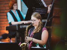 Junge Frau spielt Saxofon, im Hintergrund ist eine Pianistin zu sehen