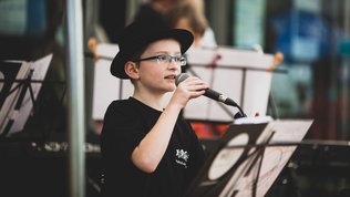 Sänger Musikschulband die Planeten Junge mit Mikro und Hut