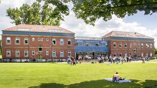 Gebäude der Musikschule Fürth im Südstadtpark an einem Sommertag, davor viele Menschen