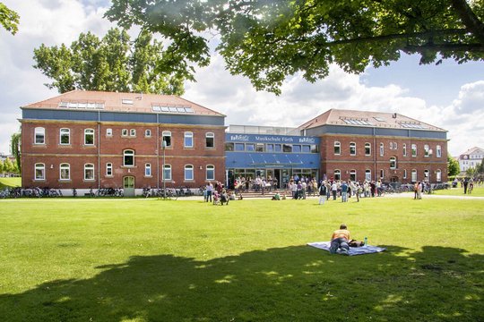 Das Gebäude der Musikschule Fürth im Südstadtpark, davor viele Menschen in der Sonne