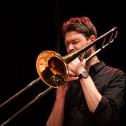 Posaunenlehrer Christoph Müller spielt mit geschlossenen Augen Posaune