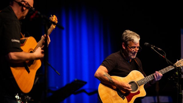 Gitarrist musiziert lachend auf der Bühne