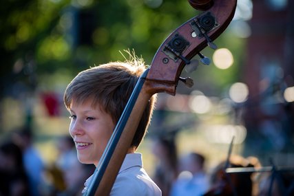 Junge mit Kontrabass, im Freien, die Sonne scheint