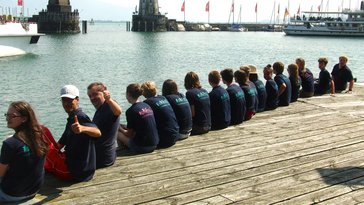 Mitglieder der Band Vollgas Connected sitzen auf Holzsteg am Wasser